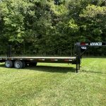For sale in Ohio: a 20k Tandem Dual Gooseneck Trailer branded Advanced. This dual axle flatbed, surrounded by dense trees and resting on grass, features rear loading ramps.